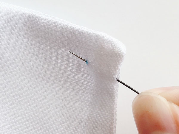 縫い目の間から針を入れて玉結びを隠します
